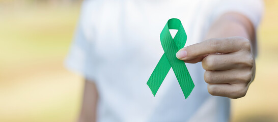 Woman holding green Ribbon for supporting people living and illness. Liver, Gallbladders bile duct, kidney Cancer and Lymphoma Awareness month concept