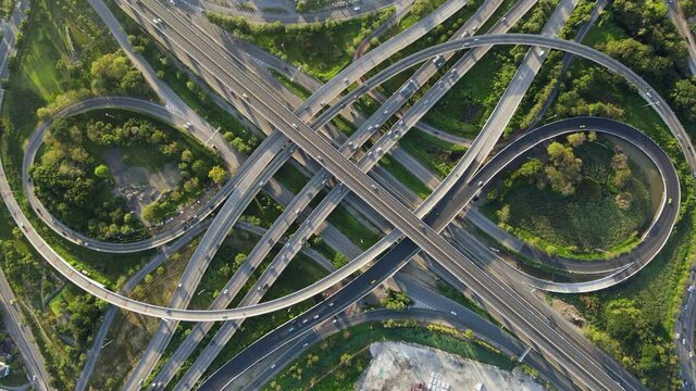 4K. Aerial view of road interchange or highway intersection with busy urban traffic speeding on the road. Junction network of transportation taken by drone.