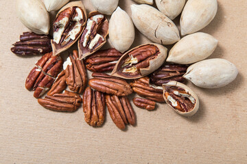 Peeled pecans, in the shell and without. Carya illinoinensis nuts laid out on a cardboard background.