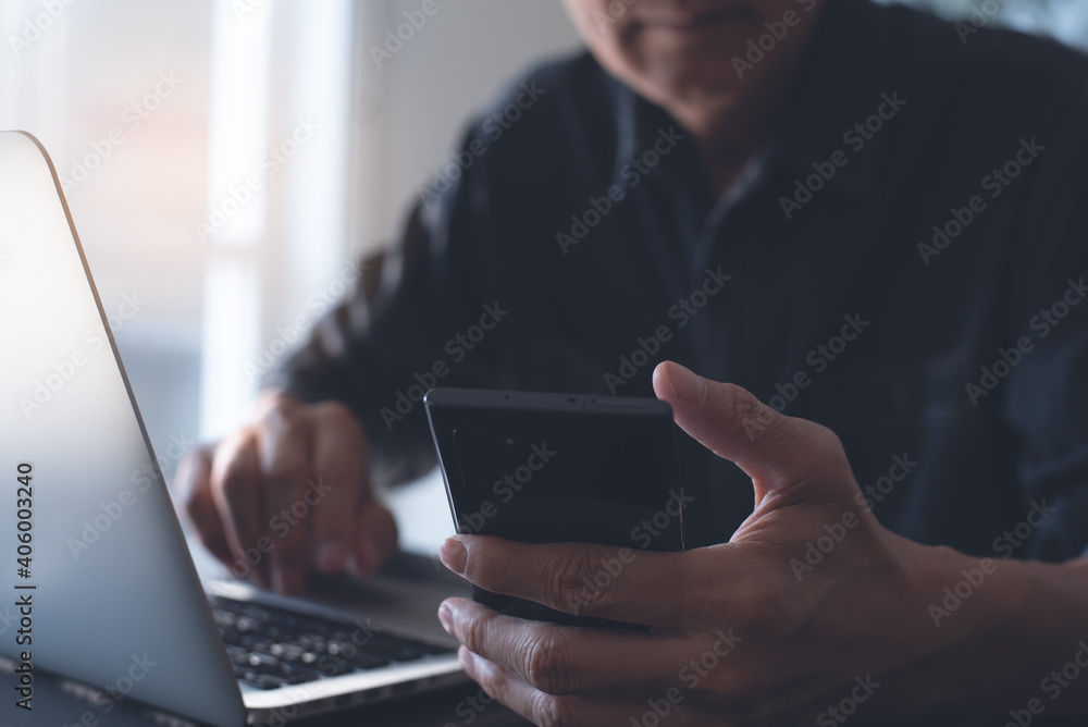 Aufkleber closeup of man using mobile phone during working on laptop computer on office table
