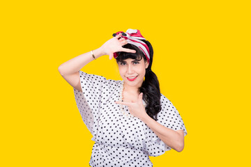 Wow, Closeup red head young woman pretty amazed pinup girl in button shirt excited surprised shocked looking up to side retro vintage 50s hairstyle on yellow wall. Cute face expression