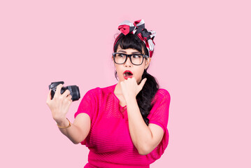 
Portrait of a beautiful asian young woman taking picture by digital camera on pink background.