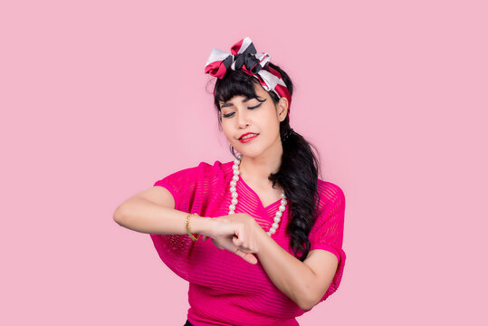 Wow, Look here aside. Closeup red head young woman pretty amazed pinup girl in button shirt excited surprised shocked looking up to side retro vintage 50s hairstyle on pink wall. Cute face expression