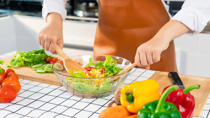 woman in the process of preparing healthy food Vegetable Salad mixing salad wooden spoon in kitchen at home Dieting Concept