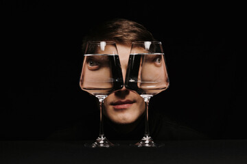 portrait of a strange man looking through two glasses of water