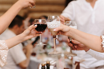 people's hands clink glasses with alcoholic beverages