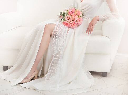 wedding photo with a white dress and a bouquet of pink roses on a light background
