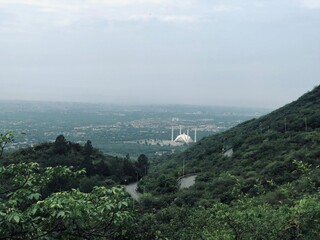 Beautiful white Faisal Mosque can be seen in green margalla hills or mountains