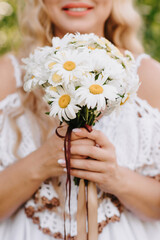 wedding bouquet of daisies in the hands of the bride