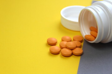 Orange pills lie on yellow and gray