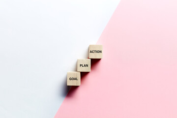 The words goal, plan and action on wooden cubes against pink and white background. Business or marketing planning strategy - obrazy, fototapety, plakaty