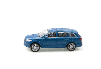 Blue toy off-road vehicle with rain drops isolated on white background. Washed car. Copy space
