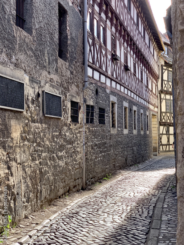 Poster Vertical shot of a narrow cobblestone road going through old stone-made residential buildings