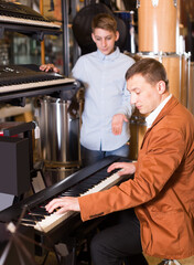Males buyers choose a synthesizer in the music store
