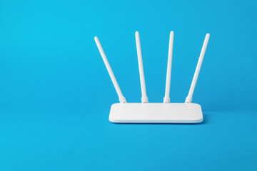 White Wi-Fi router with external antennas on a blue background. - obrazy, fototapety, plakaty