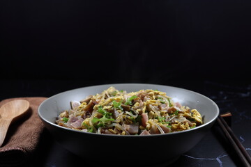 Fried and stirred rice noodle with egg, cutting fresh wing bean and pork ham seasoning with soy sauce and pepper serving on the plate. Famous comfortable breakfast menu in Asia restaurant. 