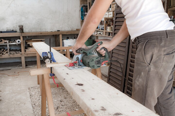 Male carpenter working with wood material in a garage.