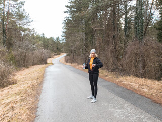 Adult caucasian woman in 40s exercising / jogging on a suburb road in winter / autumn season time.