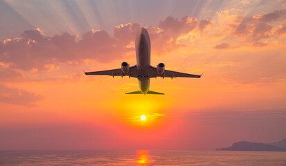 Fototapeta na wymiar Airplane flying over tropical sea at sunset