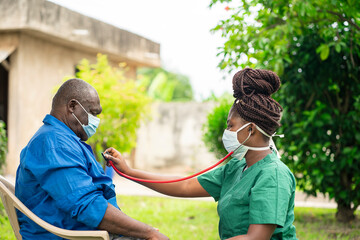 image of african man with face mask, braided black woman in face mask  holding stethoscope- home health care concept - obrazy, fototapety, plakaty