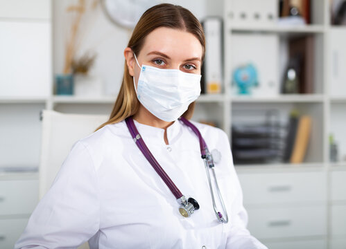 Female doctor in lab coat and protective medical masks works at the laptop