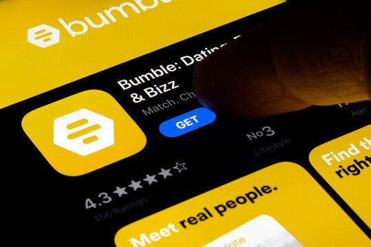 Hand holding a smartphone with a Bumble dating app on apple store at night. IPhone 11 with a social media Bumble app logo. Find your match. 