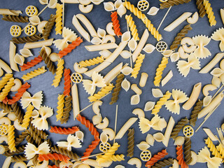 Obraz premium colored different types of Italian pasta on a dark background. food texture. flour products and food in cooking