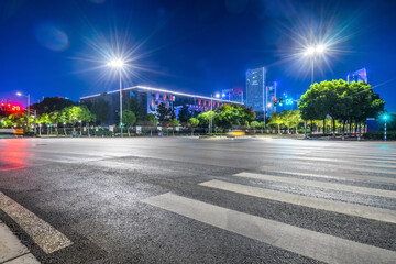 empty road with zebra crossing and skyscrapers in modern city at night
