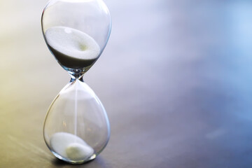 Sand running through the bulbs of an hourglass measuring the passing time in a countdown to a...