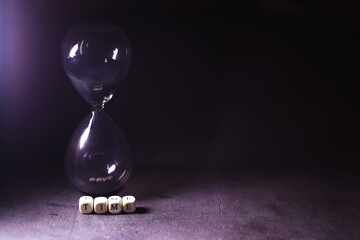 Sand running through the bulbs of an hourglass measuring the passing time in a countdown to a...