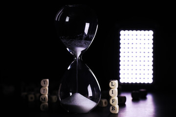 Sand running through the bulbs of an hourglass measuring the passing time in a countdown to a...