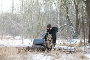 Outdoor portrait of handsome man in coat and scurf. Bearded man in the winter woods.