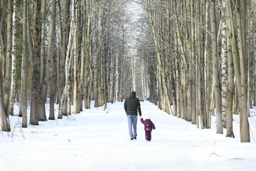 Happy family playing and laughing in winter outdoors in the snow. City park winter day.