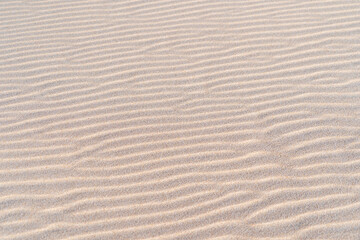 White sand texture waves close up. Wavy background pattern of sandy beach. 