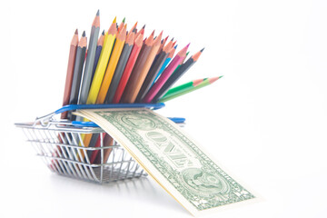set of colored pencils for drawing in a market basket with a dollar bill. sales marketing