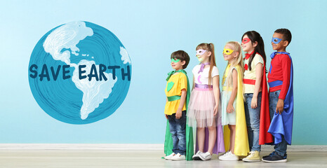 Cute little children dressed as superheroes near drawing of planet on color wall. Earth Day celebration © Pixel-Shot