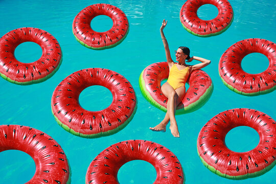 Beautiful young woman with inflatable rings relaxing in swimming pool