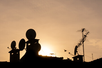 old television antennas and dish antenna silhouettes on the roof