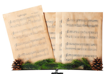 Music sheets with notes and Christmas decor on stand against white background