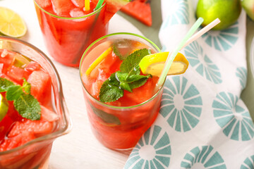 Glasses and jug of tasty cold watermelon lemonade on table