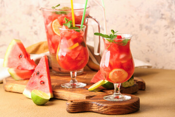 Glasses and jug of tasty cold watermelon lemonade on table