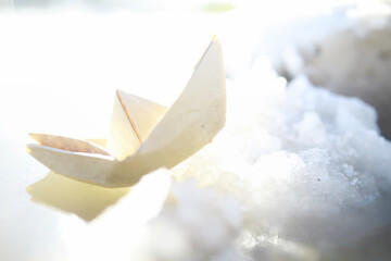 Paper boat in the water on the street. The concept of early spring. Melting snow and an origami...
