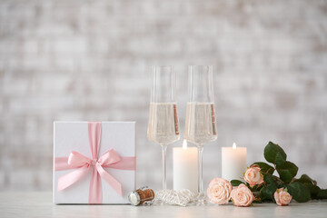 Glasses of champagne, flowers, candles and gift for Valentine's Day on table
