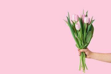 Hand with bouquet of beautiful tulips on color background