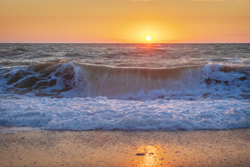 Wave on sea shore during the sunset.