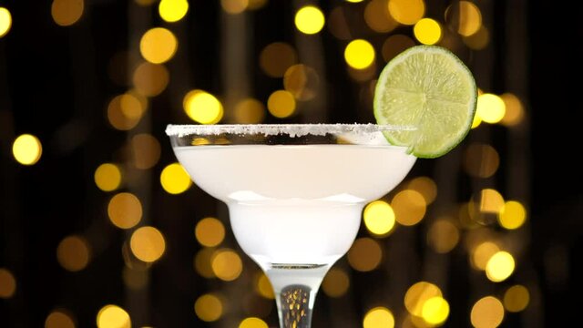 Margarita cocktail from tequila and lemon over Bokeh Blinking background. Glass with a cocktail. Party, Success, holiday celebrating