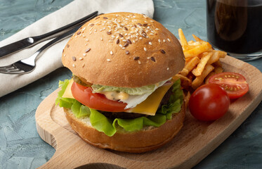 Burger with a drink and French fries. Still life with a Burger. Burger with fresh lettuce leaves.