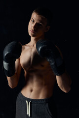 Fototapeta na wymiar sports guy on a black background in boxing gloves inflated torso cropped view Model Copy Space