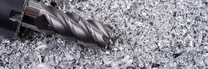 Panoramic image. Silver end mill cutter with metal shavings. Processing of ferrous metals in a factory