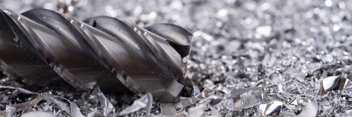Panoramic image. Silver end mill cutter with metal shavings. Processing of ferrous metals in a...